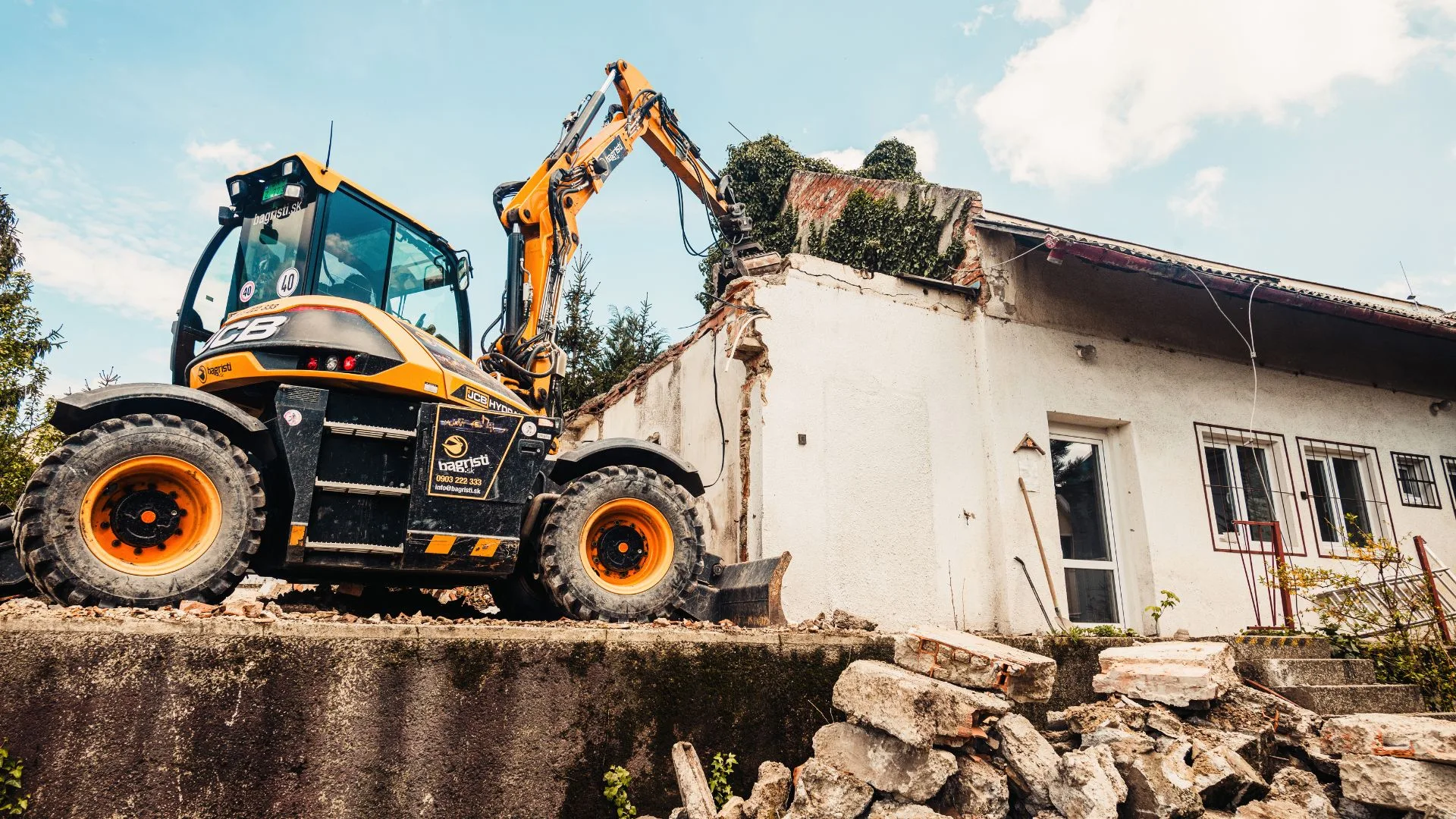Telescopic loader carefully demolishing a residential structure